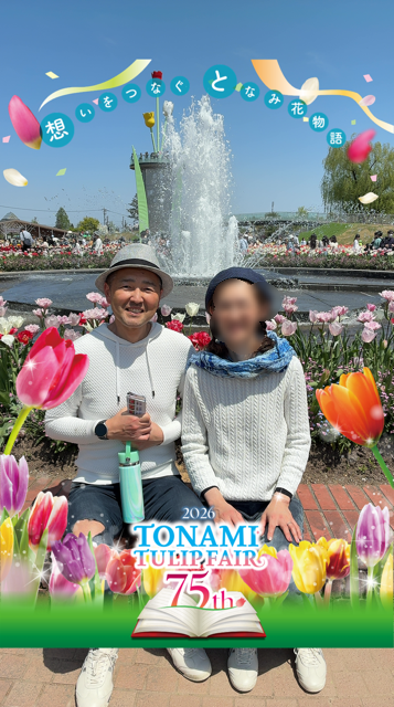 Two people sit by a fountain in a tulip garden at Tonami Tulip Fair 2026 (75th anniversary), framed by colorful petals.